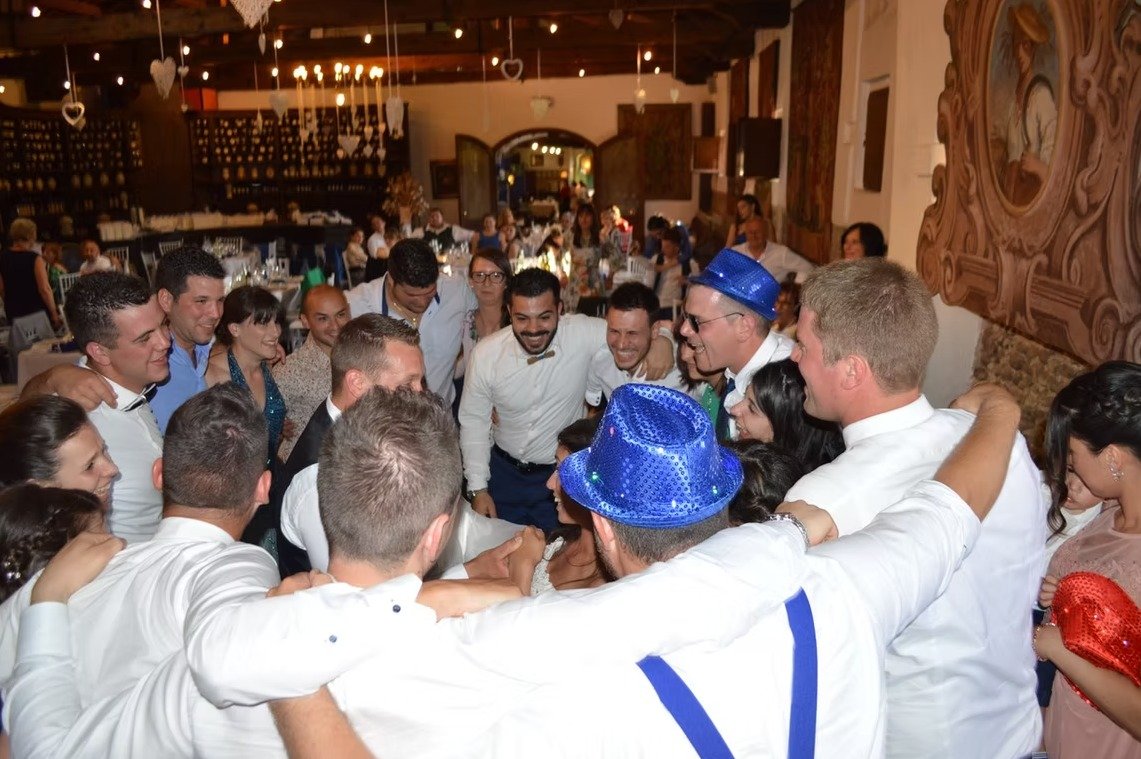 Invitati abbracciati in cerchio durante un matrimonio o una festa.