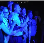 Gruppo di invitati che ballano in cerchio durante una festa con musica dal vivo.