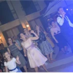 Famiglie che ballano e sorridono insieme all’aperto durante il ricevimento di matrimonio.
