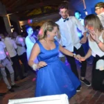 Donna che balla sorridente in abito blu durante una festa di matrimonio animata da musica dal vivo.