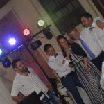 DJ e musicisti sorridenti accanto alla consolle durante un evento musicale di matrimonio.