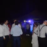 Ospiti che ballano e chiacchierano all’aperto di notte durante una festa di matrimonio con musica e luci colorate.