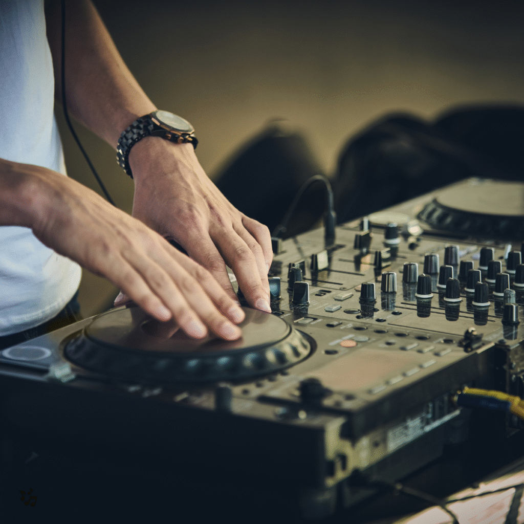DJ che mixa musica con console professionale, mani sui piatti e mixer pieno di controlli.
